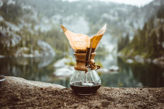 Chemex coffee brewer sits on a rock overlooking a lake